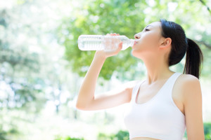 young chinese woman drinking water after jogging
