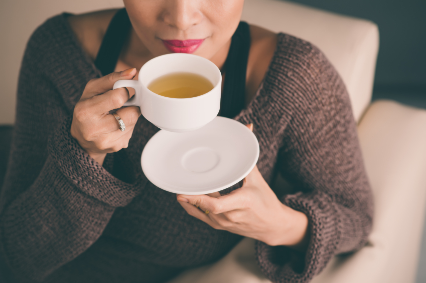 Unrecognizable woman holding a hot cup of tea and blowing on it